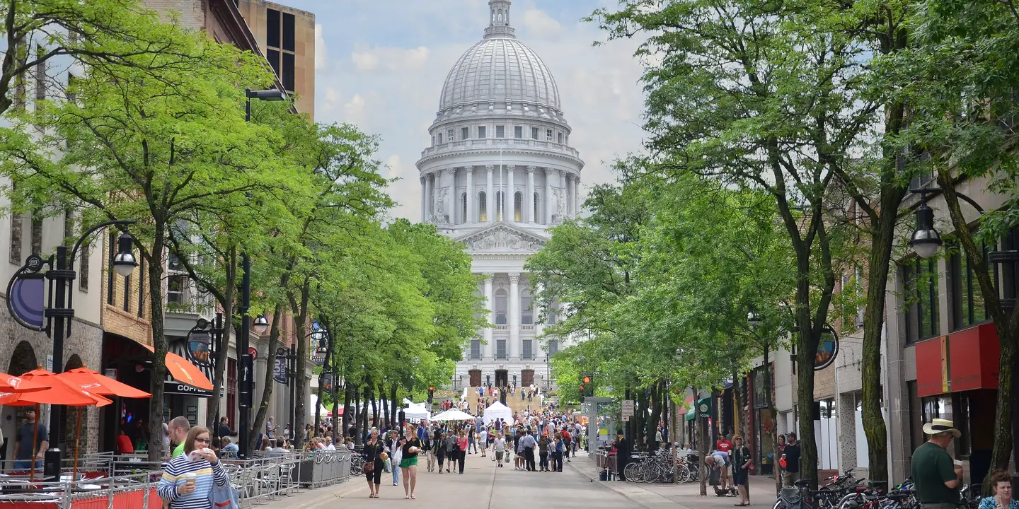 Pedestrian street leading to the domed Wisconsin State Capitol, with market crowds in the distance