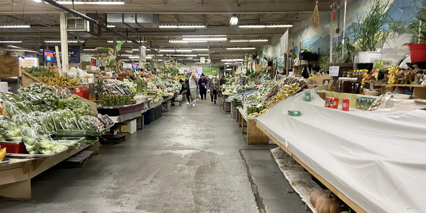 Indoor market hall with long tables of fresh vegetables and greens